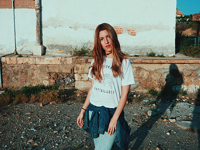 woman standing near white concrete wall casting shadow during daytime thumbnail