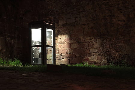 Telephone Booth Beside Brown Wall during Nighttime thumbnail