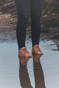 person wear black skinny jeans and brown leather boots standing on body of water thumbnail