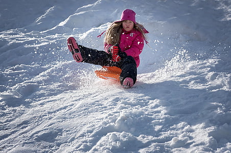 woman riding on orange board sliding on snow filled mountain thumbnail