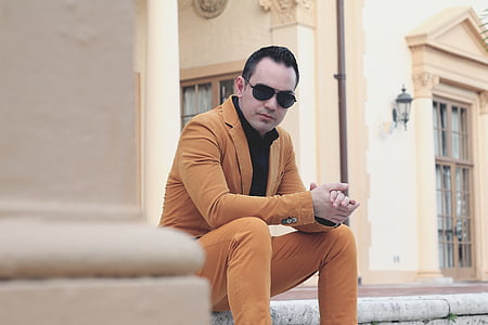 man wearing brown suit sitting on concrete thumbnail