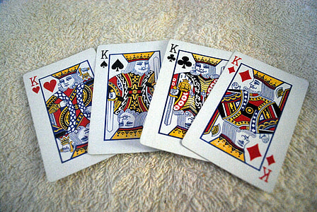 four heart, spade, clubs, and diamond Kings play cards on mat thumbnail