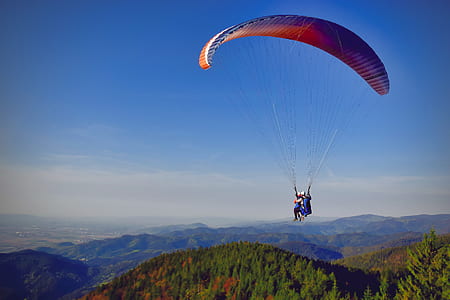two person paragliding above green mountains thumbnail