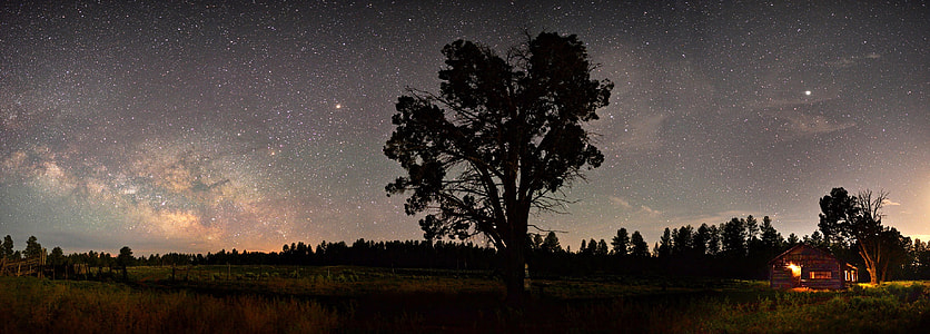 Stars and the Milky way over the night landscape with cabin and tree thumbnail