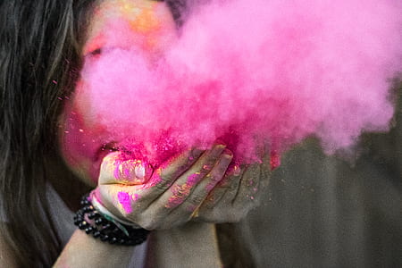 Shallow Focus Photograph of Woman Blowing Pink Powder thumbnail