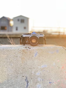 black and gray Olympus camera resting on concrete surface selective focus photography thumbnail