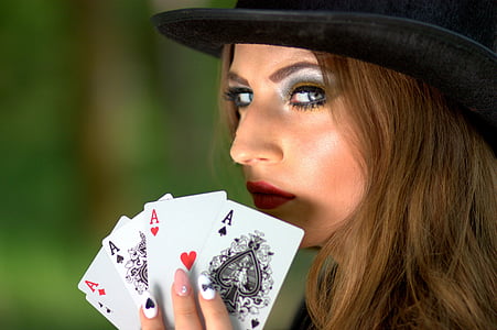 woman wearing black hat holding ace playing cards thumbnail