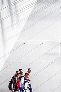 people walking baside white wall thumbnail
