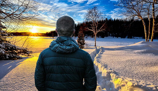 Photo illustration of man walking through snowy winter landscape during sunrise thumbnail