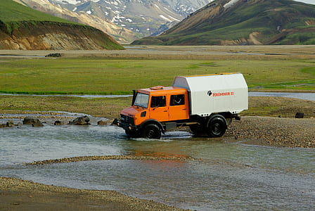 orange and white heavy equipment parked near body of water thumbnail