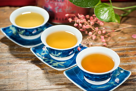 three white-and-blue cups filled with brown translucent liquids on saucers thumbnail