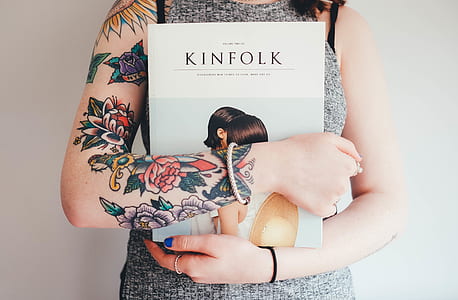 woman holding book standing near wall thumbnail