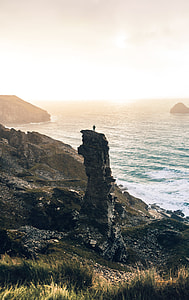 person standing on rock near sea thumbnail