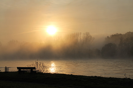 silhouette of bench near calm body of lake during sunset thumbnail