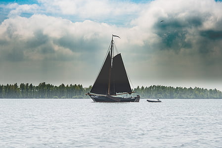 boat sailing on body of water under cloudy daytime thumbnail