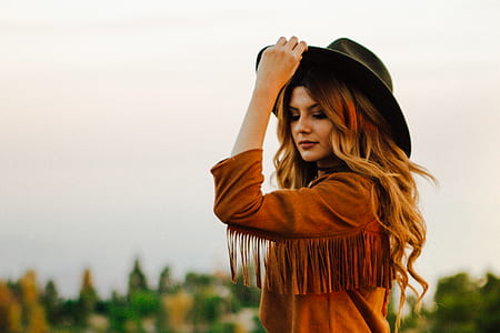 woman wearing brown top with fringe and left hand holding cowboy hat brim thumbnail