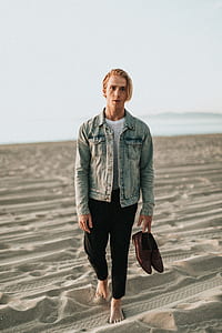 man standing on sand barefoot holding brown dress shoes at daytime thumbnail