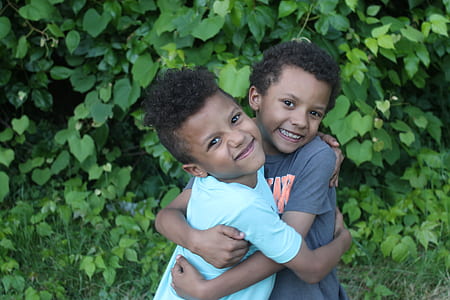 two boys hugging near green leaf plant thumbnail