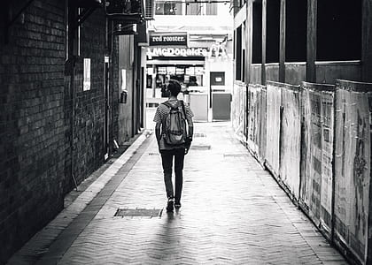 grayscale photo of man walking in a pavement towards McDonalds thumbnail