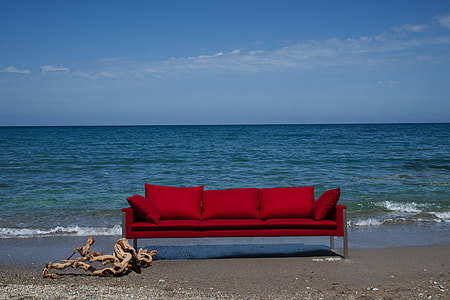 red fabric 3-seat sofa near ocean during daytime thumbnail