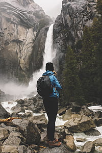 photo of man facing waterfalls during daytime thumbnail