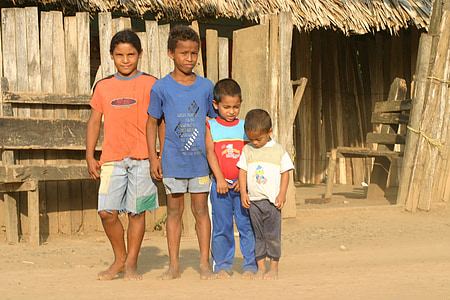four boys standing near hut thumbnail