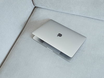 silver MacBook on gray fabric sofa thumbnail