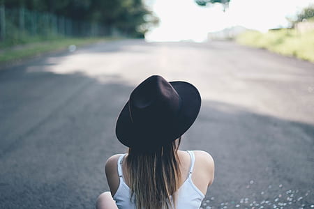 woman in white tank top with black hat sitting on ground thumbnail