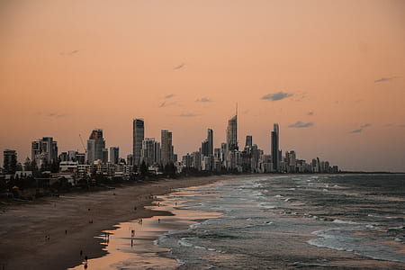 photo of group of people on seashore near high-rise buildings thumbnail