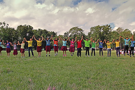 group of student holding hands on green field during daytime thumbnail