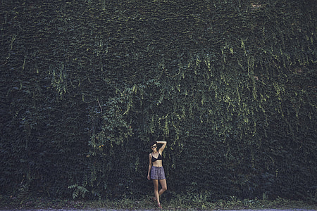 woman wearing red bra and brown shorts standing near green wall thumbnail