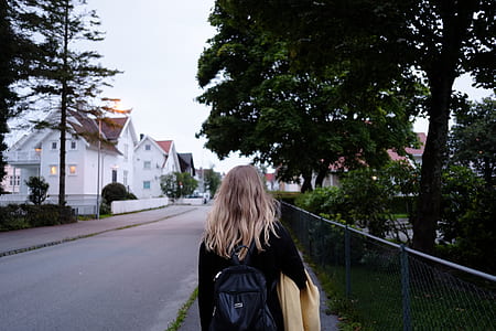 woman wearing backpack standing beside fence thumbnail