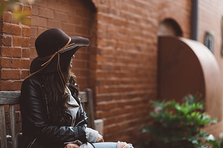 woman in black jacket sitting on brown bench thumbnail