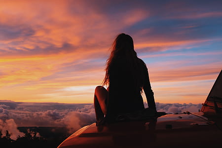 woman sitting on vehicle hood at golden hour thumbnail