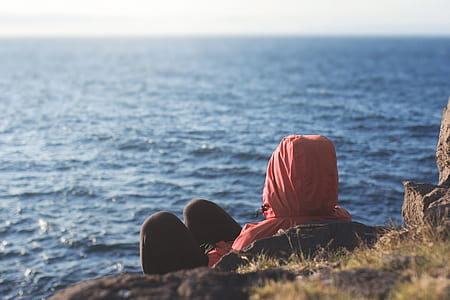 person laying on rock facing body of water thumbnail