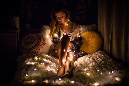 silhouette photography of woman lying on bed with string lights thumbnail