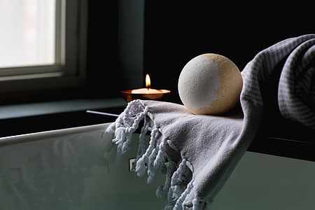 white and brown ball on top of gray cloth near lighted candle thumbnail