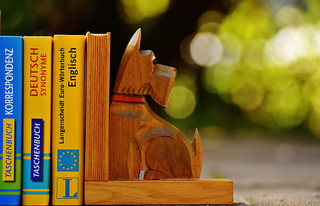 brown dog wood sculpture bookend beside three textbooks thumbnail