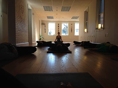 silhouette of people doing yoga inside brown wooden floor room thumbnail
