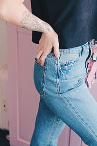 woman wearing blue denim bottoms while standing beside pink wooden cabinet thumbnail