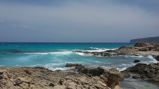body of water and rock formations during daytime thumbnail