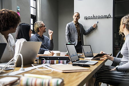 man standing in front of people while pointing marker on white board thumbnail
