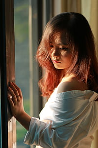 woman wearing white dress shirt standing near window thumbnail