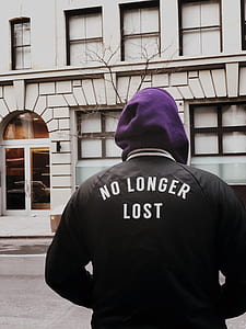 person wearing hoodie standing in front of concrete building thumbnail