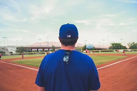 person wearing blue t-shirt standing near baseball field during daytime thumbnail