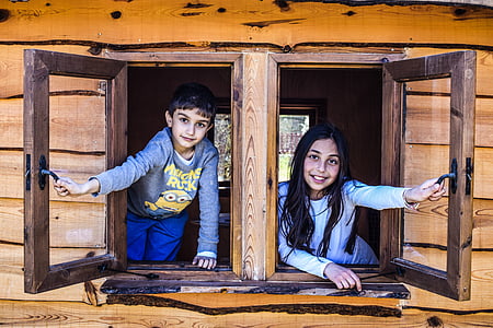 boy and girl looking holding two brown wooden window frames thumbnail