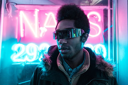 person wearing sunglasses standing near neon sign thumbnail