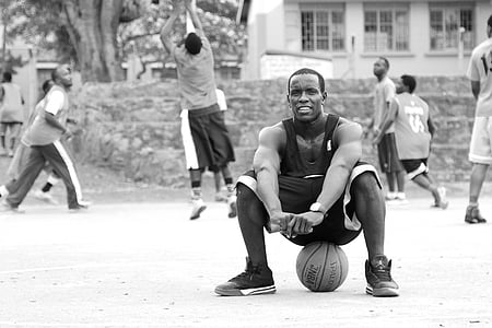 grayscale photo of man sitting on basketball thumbnail