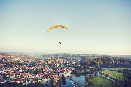 aerial photography of person with parachute over houses thumbnail