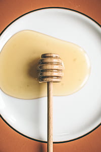 beige honey dipper on round white ceramic plate thumbnail